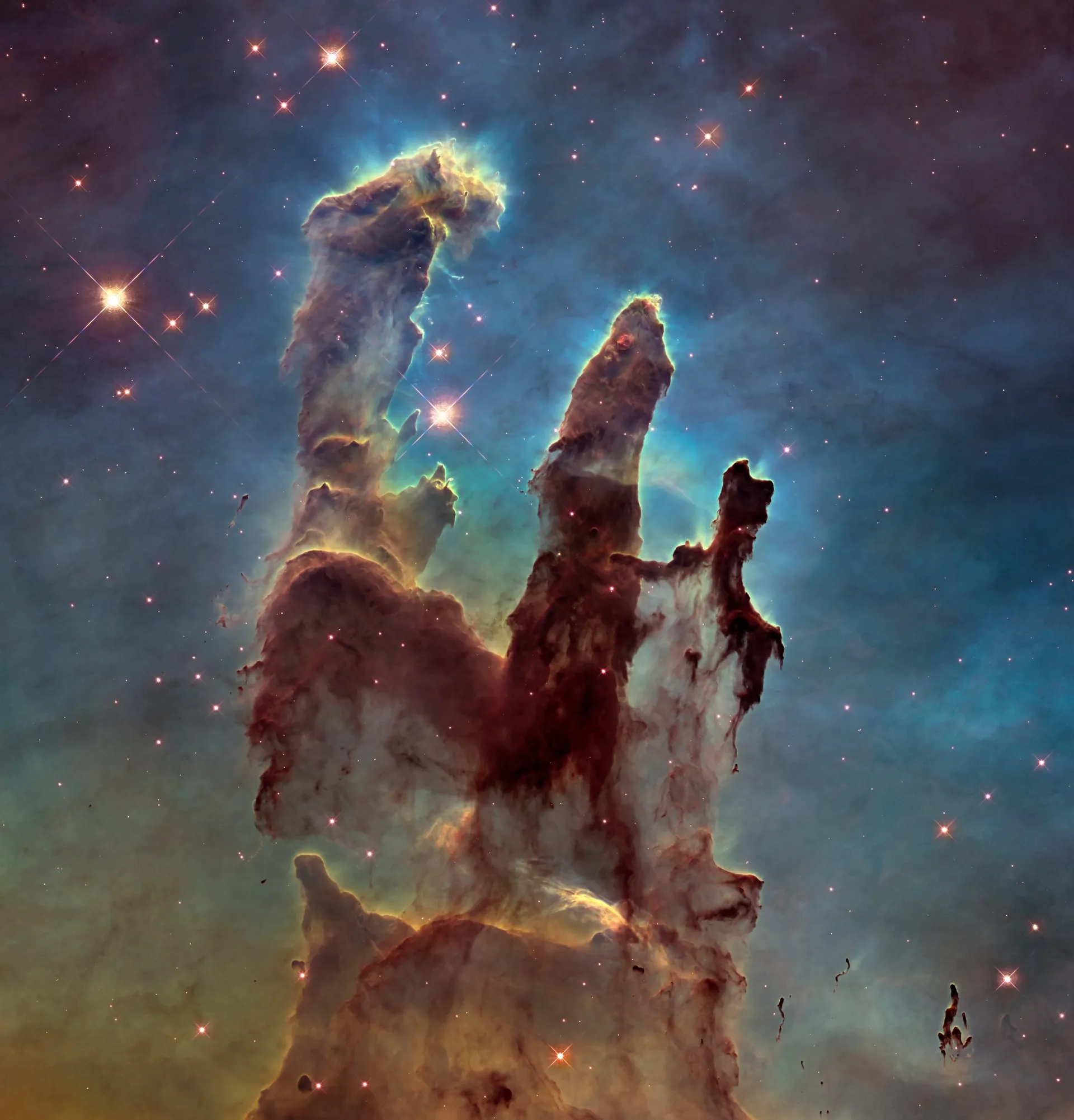 Hubble's photograph of the Pillars of Creation: columns of dust rising through glowing blue-green gas.